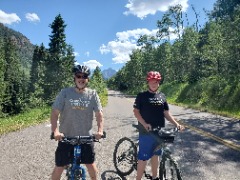 Dave Reed and son Jackson mountain biking in Aspen, Colorado, with one of the Maroon Bells in the background.